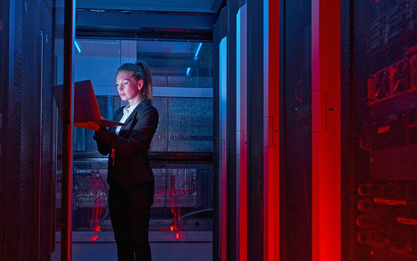 A woman is positioned in a server room as she monitors the complex array of servers and equipment.