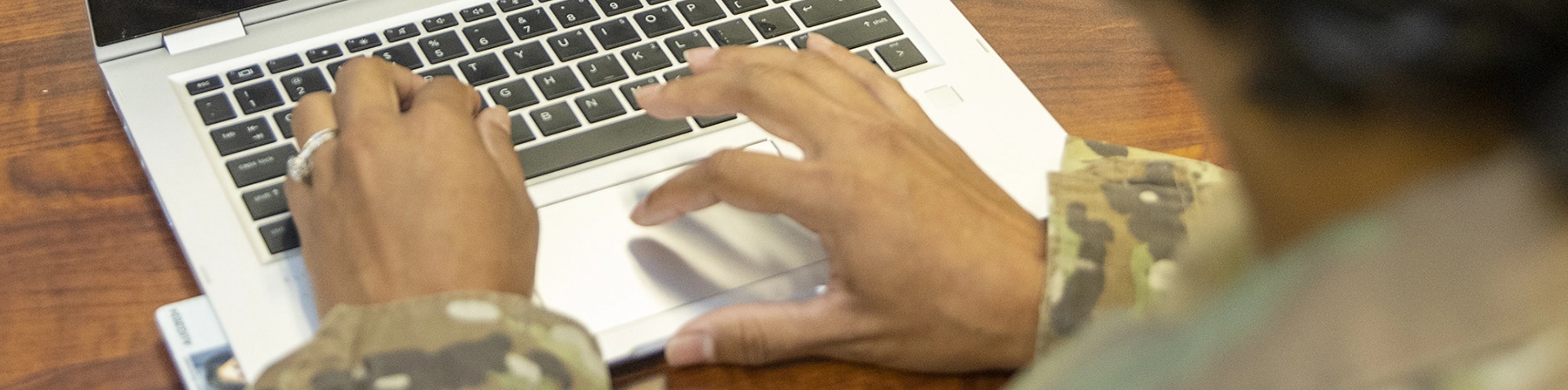 A U.S. Army soldier typing on a laptop computer.