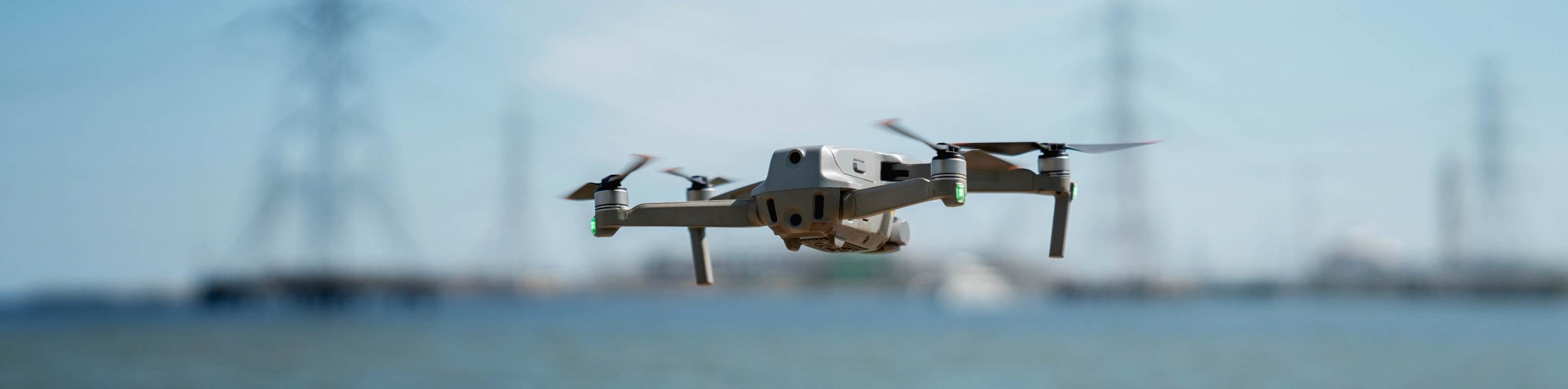 A small drone hovers above a tranquil body of water, capturing the serene landscape from above.