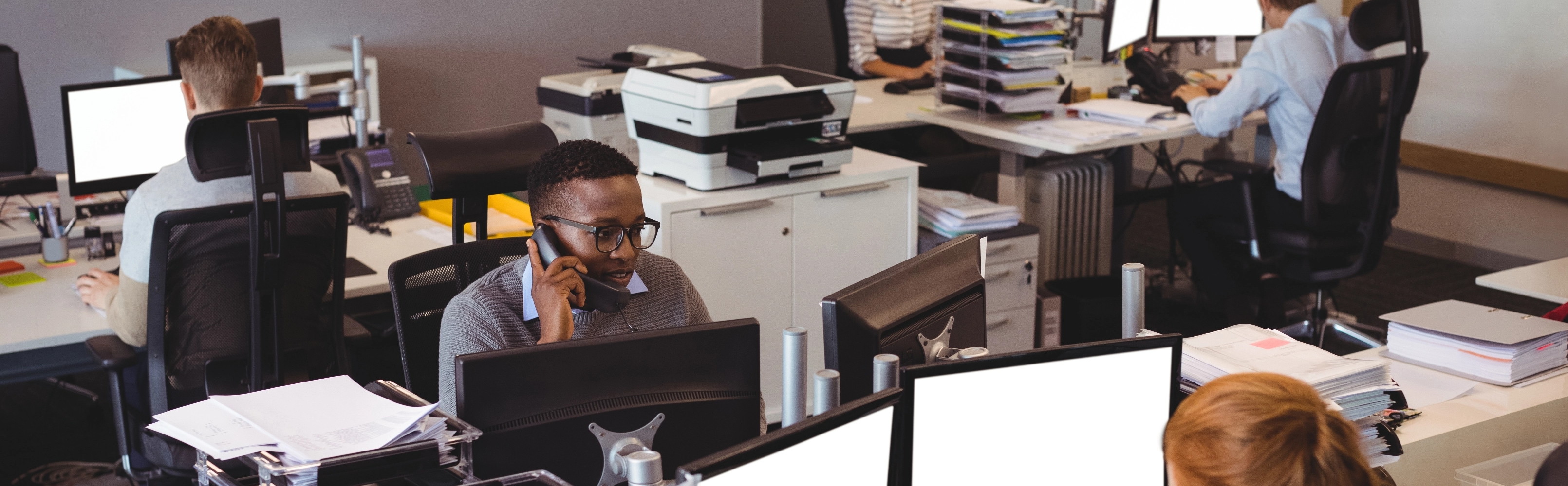 A group of professionals focused on their tasks at individual desks in a collaborative office environment.