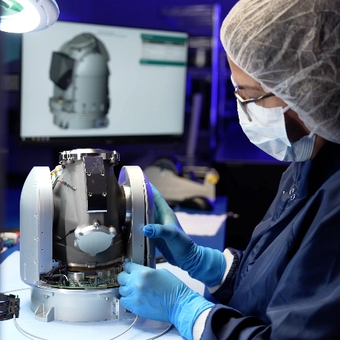 A lap technician inspecting a microscope.