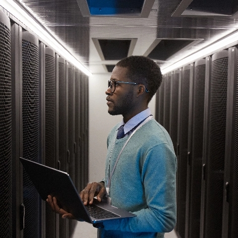 A man inspecting a row of networking racks.