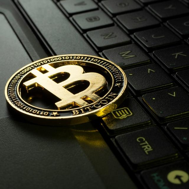 A bitcoin logo on top of a black keyboard.